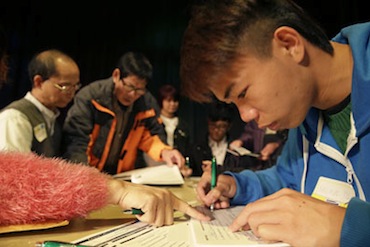 Shuxun Yu, right, 19, of Oakland, was given assistance filling out an application form during a health care enrollment event in March at the Oakland Asian Cultural Center (Photo by Eric Risberg/AP). 
