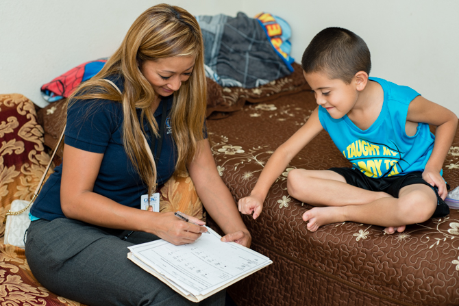 During a home visit, health educator Nunu Sixay sits down with 6-year-old Jovani Garcia-Vasquez and asks him to point out how his asthma felt that day (Photo by Heidi de Marco/KHN).