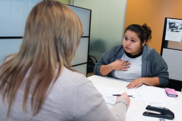 The eligibility worker at the Department of Public Social Services county office tells Marcy she needs proof that she was in foster care.  Without a universal database for foster children, social service providers have difficulty finding their records (Photo by Heidi de Marco/KHN).
