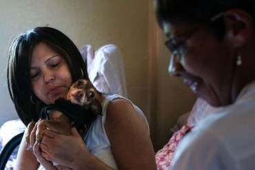 Sandra Lopez and her dog Coco greeting hospice nurse Heather Meyerend last fall. In the weeks before Lopez died, Meyerend stopped by weekly to check her physical health, pain levels and medications. (Photo by Amy Pearl/WYNC)