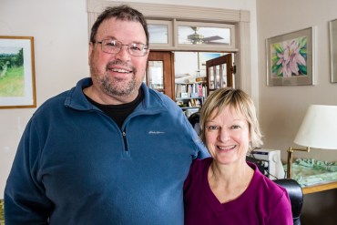 Married couple David Fairchild and Clara Peterson stand in the living room of the Story City home. They own a small cleaning business and were on CoOpportunity Health before it faltered (Photo by Clay Masters/IPR)