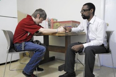 Rome Tucker, 36, prays with his roommate Jarrod Landers, 20, left, at their apartment above Thresholds Psychiatric Rehabilitation Center in Blue Island on April 1, 2015. (Photo by Michael Tercha/Chicago Tribune)