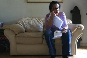 Angela Denig, who has chosen to live without health insurance and pay the Affordable Care Act penalty for being uninsured, holds her medical bills in her Florida home. Months after Denig, 41, chose to pay the penalty, she was diagnosed with a benign tumor in her breast and the cost of surgeries soaked up her savings. (Photo by Charles Trainor Jr./Miami Herald)