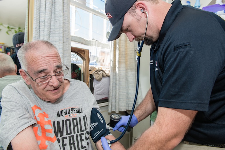 Paramedic Ryan Ramsdell checks 68-year-old Earl Mayes blood pressure during a home visit on March 26, 2015 in Sparks, Nevada. Ramsdell is part of a community health plan to help reduce avoidable emergency room visits by treating patients at home (Photo by Heidi de Marco/KHN).