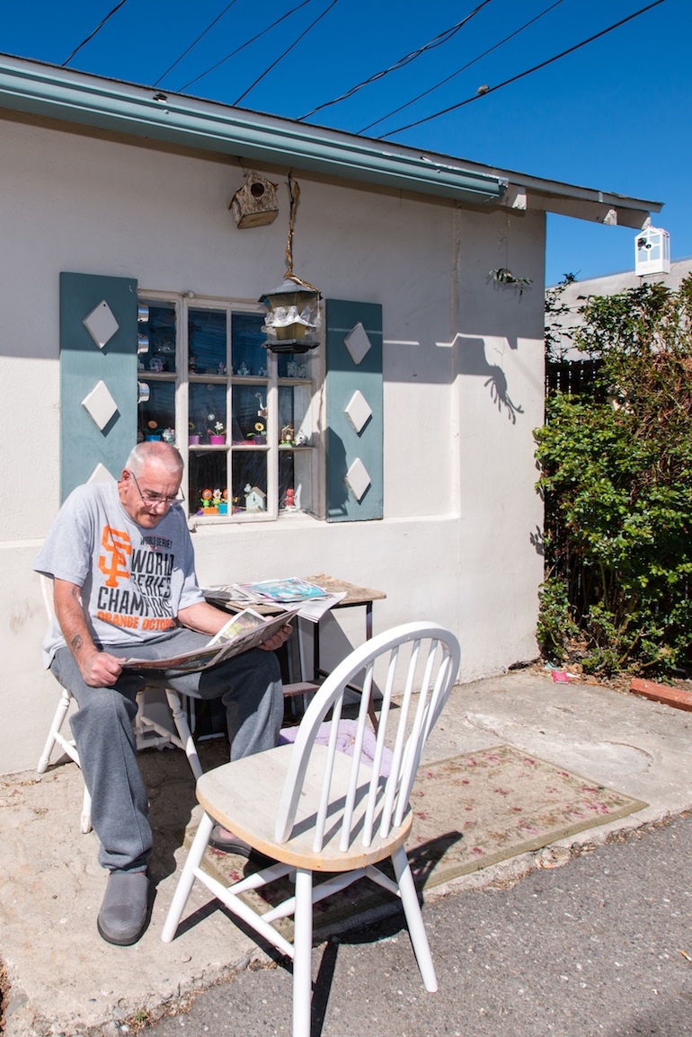 Mayes returns to reading his newspaper in front of his one-bedroom house after his check up. Mayes is scheduled to have another surgery in May. “I hope that works out good for me,” he said (Photo by Heidi de Marco/KHN).