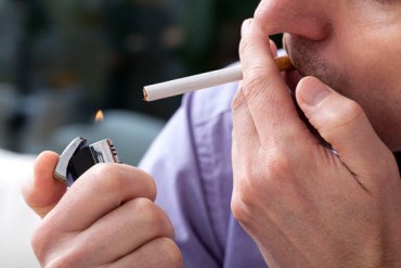 Young man lighting up a cigarette with a lighter,closeup