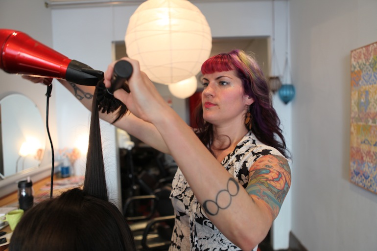 Mardi Palan cuts a client's hair at Gilly’s Salon in Portland. Palan plans to use the $30,000 she could get for carrying twins, for a downpayment on a home.  (Photo by Kristian Foden-Vencil/Oregon Public Broadcasting)