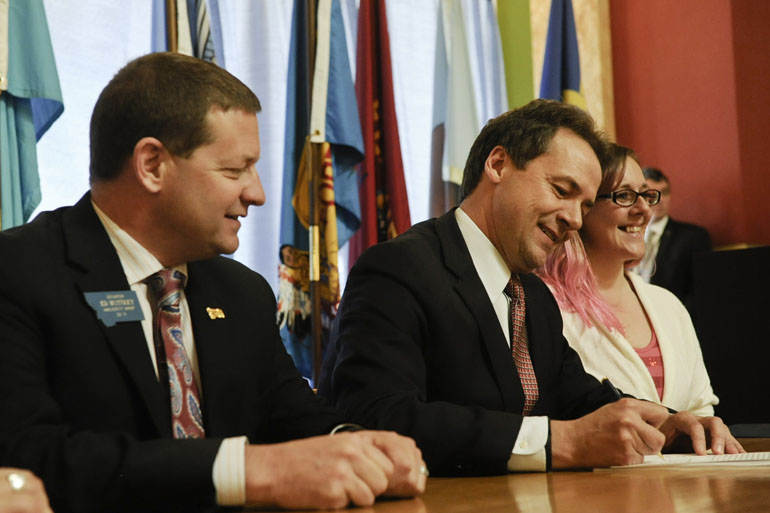 Democratic Gov. Steve Bullock, center, signs a bill to expand Medicaid to about 70,000 low-income Montanans in April. (Thom Bridge/Independent Record via AP)