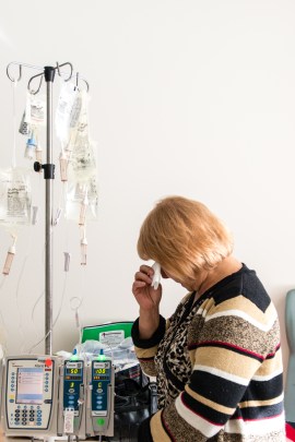 Jose Garcia Flores’ wife stands quietly at her husband’s bedside on Tuesday, October 13, 2015 (Photo by Heidi de Marco/KHN).