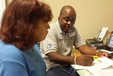 Harriet Cohen, 63, gets help enrolling in a health plan for under $7 a month at the Greenacres, Fla., library from navigator Abdius Pierre Cohen who lives in Boynton Beach, Fla. (Photo by Phil Galewitz/KHN)