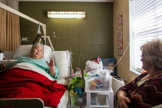 Wanda Chism, left, talking to Pam Bates, an administrator at Generations of Red Bay. Ms. Chism cannot walk on her own, and patients like her need to be repositioned every few hours to avoid dangerous pressure ulcers. (Photo by Joe Buglewicz for The New York Times)