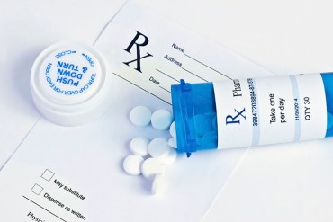 Blue prescription bottle with white pills and prescription.