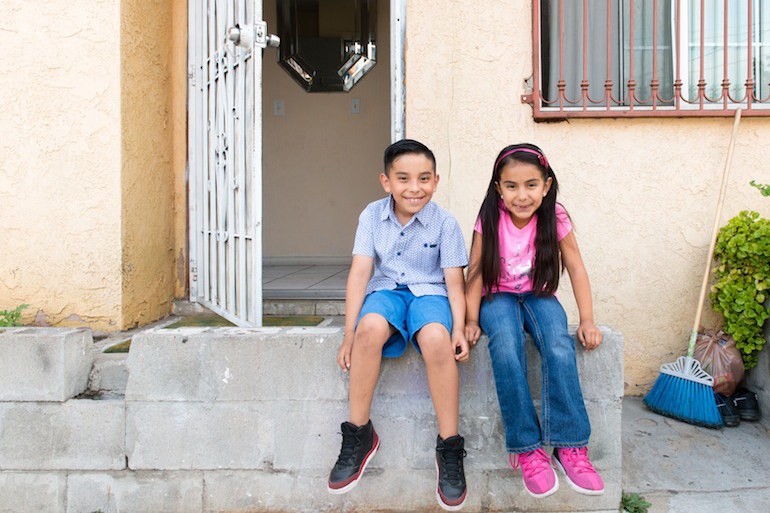 Siblings Benito and Stephanie sit on the front porch of their house in Los Angeles, Calif., on May 31, 2016. The children learned about earthquake preparedness at school and decided the porch would be the family’s meeting place in case of an emergency. (Heidi de Marco/KHN)