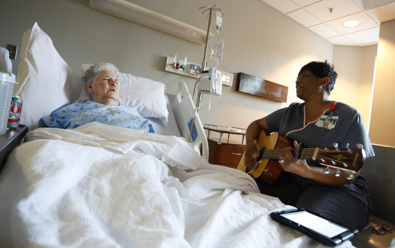 Queze Ferguson, 75, listens to music therapist Angela Howard sing and play the guitar. Ferguson was hospitalized in the geriatric unit of the University of Alabama Hospital, Birmingham. (Hal Yeager for KHN)