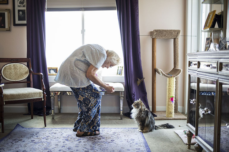 Kathy Baron with Munchkin. Baron was left disabled by breast cancer and nerve pain. InnovAge has made it possible for her to stay in her home. “I would rather be dead than go into a nursing home,” she said. (Nick Cote for The New York Times and Kaiser Health News)