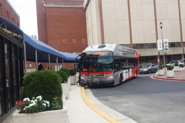 A bus arrives at the bus circle at MedStar Washington Hospital Center in the District of Columbia in July 2016. The hospital is served by many buses, vans and shuttles that come through the circle frequently. (Zhai Yun Tan/KHN)