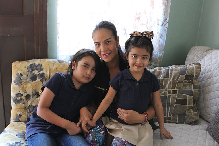 After one year of not visiting a dentist, Erika Andalon, 8, recently gained full-scope medical and dental coverage as a result of SB 75, a state law that allows children born outside the U.S. to enroll in the state’s public health program. She is pictured with her younger sister, Elaine, 4, and her mother, Erika, in their Los Angeles home on Sept. 14. (Ana B. Ibarra/California Healthline)