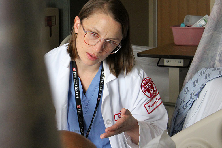 Dr. Zoe Maher interviews a shooting victim at Temple University Hospital for a citywide study of care of violent trauma victims. (Emma Lee/WHYY)