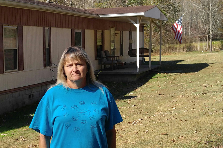 Freida Lockaby of Manchester, Ky., stands outside the mobile home she rents. She says she has benefited from gaining access to Medicaid. (Phil Galewitz/KHN)