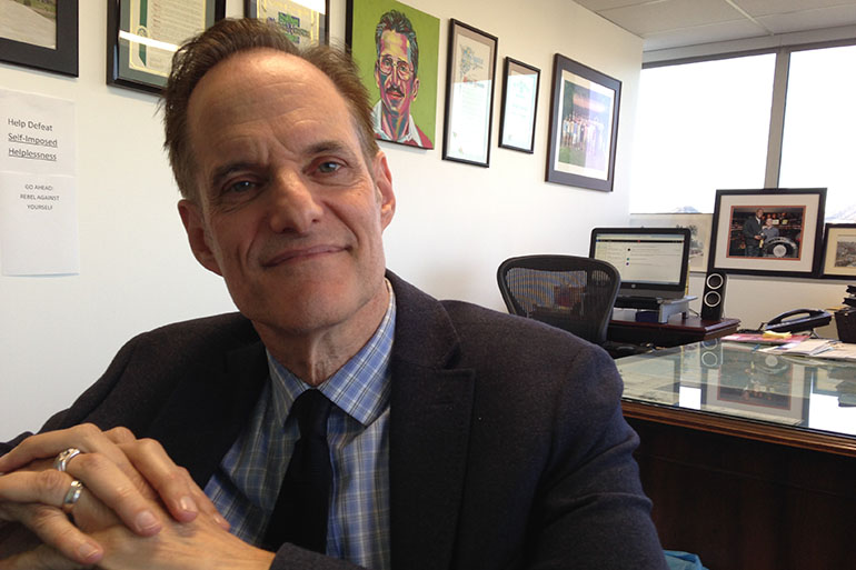 Michael Weinstein, president of the AIDS Healthcare Foundation, in his office in Los Angeles. Behind him is a painting of Chris Brownlie, who worked with Weinstein to found the first AIDS hospice in LA. He is backing Propositions 60 and 61. (April Dembosky/KQED)