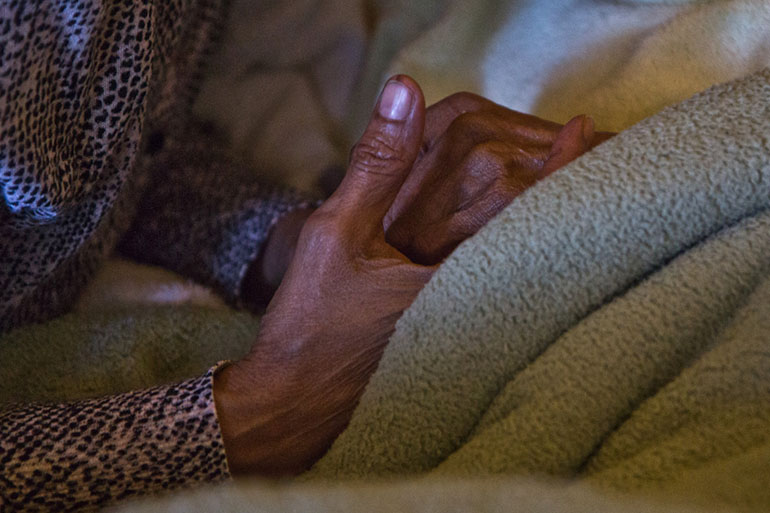 Angela Bobo holds the hand of her mother, Ruth Perez. Bobo is Perez’s at-home caregive