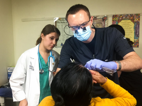 Third-year dental student Alex Dolbik checks the oral health of a patient at the Refugee Health Clinic in San Antonio. (Wendy Rigby/Texas Public Radio)
