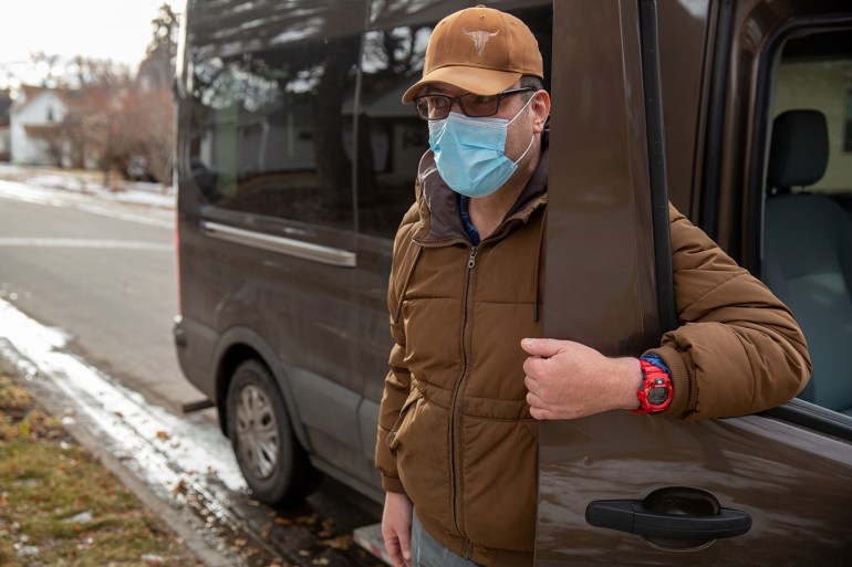 Mitch Domier stands outside beside a van, wearing a face mask