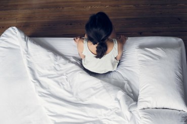 Woman sitting on edge of bed waking up