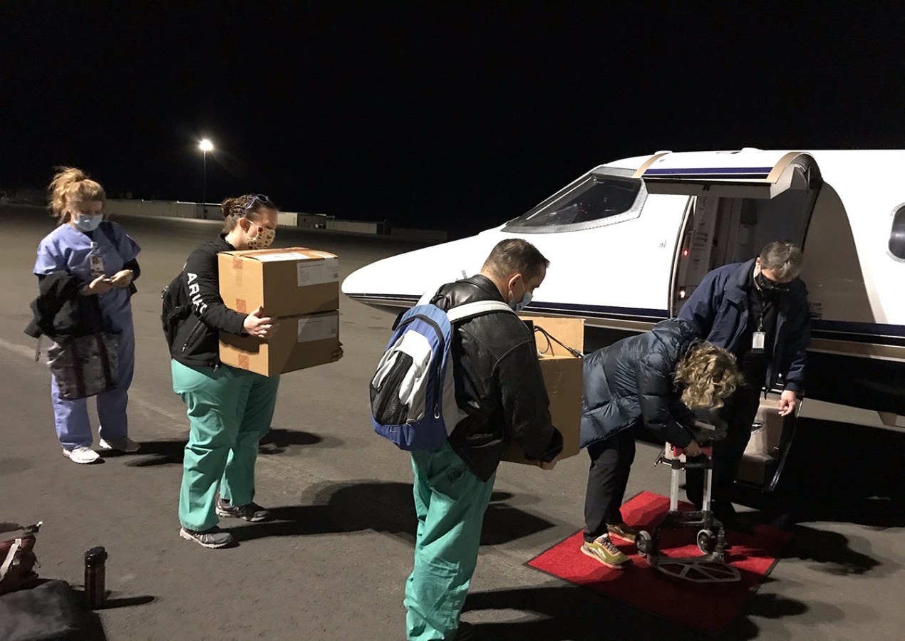 a team of five people carry boxes of vaccines
