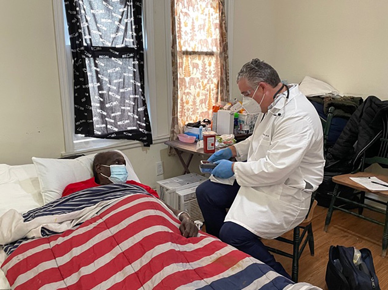 a male doctor vaccinates a senior man laying in bed