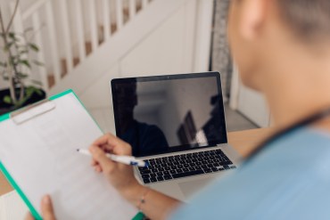 female doctor taking notes in telemedicine appointment