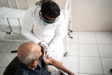 A health worker vaccinates a senior man