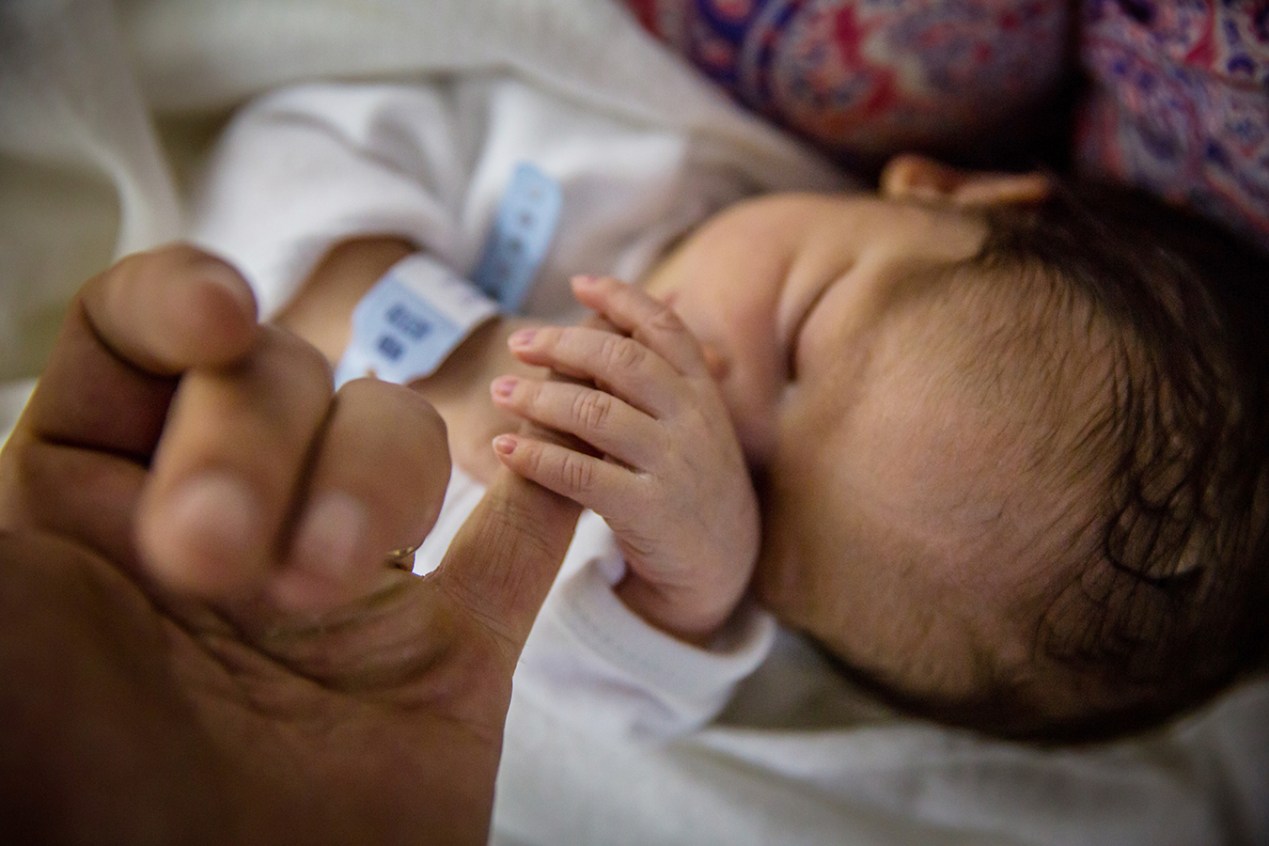 Newborn baby gripping their mother's hand