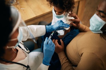 Close-up of doctor vaccinating African American girl during coronavirus pandemic.