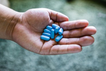 A hand holding blue Truvada pills