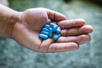 A hand holding blue Truvada pills