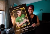 Kathi Arbini holds a poster with her son Kevin Mullane's photo