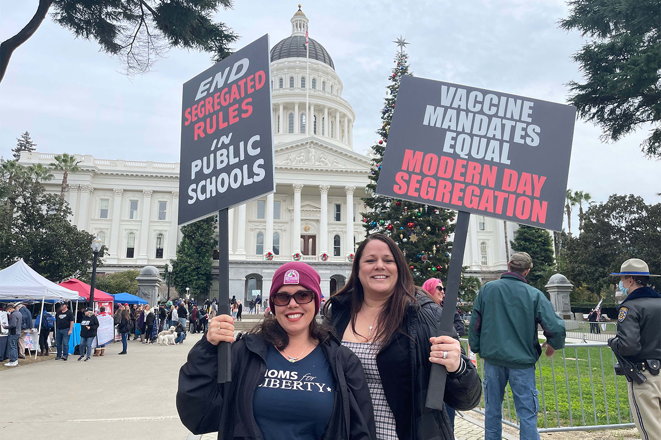 Placer County residents Nicole Young and Wendy Biel hold signs while standing in front of the California Capitol at an anti-vaccine protest in early January.