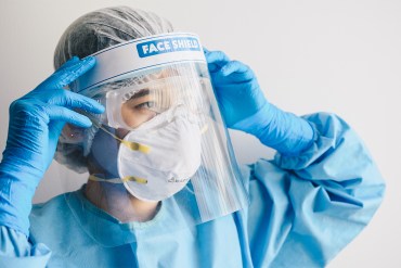 A nurse puts on a face shield.