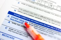 A photo of an orange highlighter resting on a health insurance sign-up form.