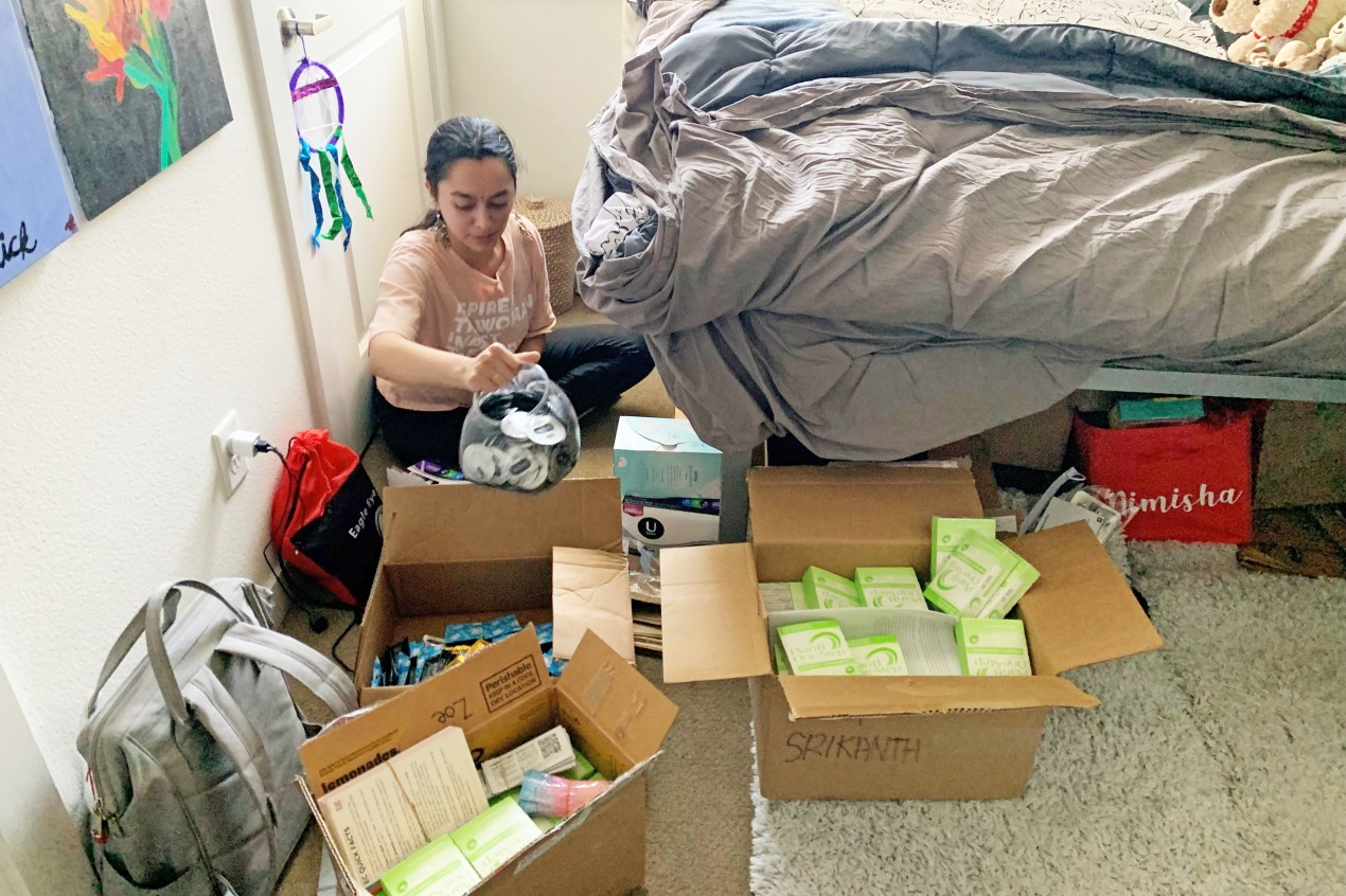 Nimisha Srikanth sits on the floor next to her bed. She is surrounded by boxes full of Plan B and condoms.