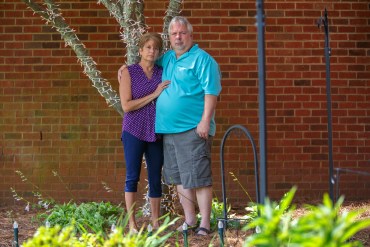 a couple stand beside a tree they light in honor for their son who died of an overdose