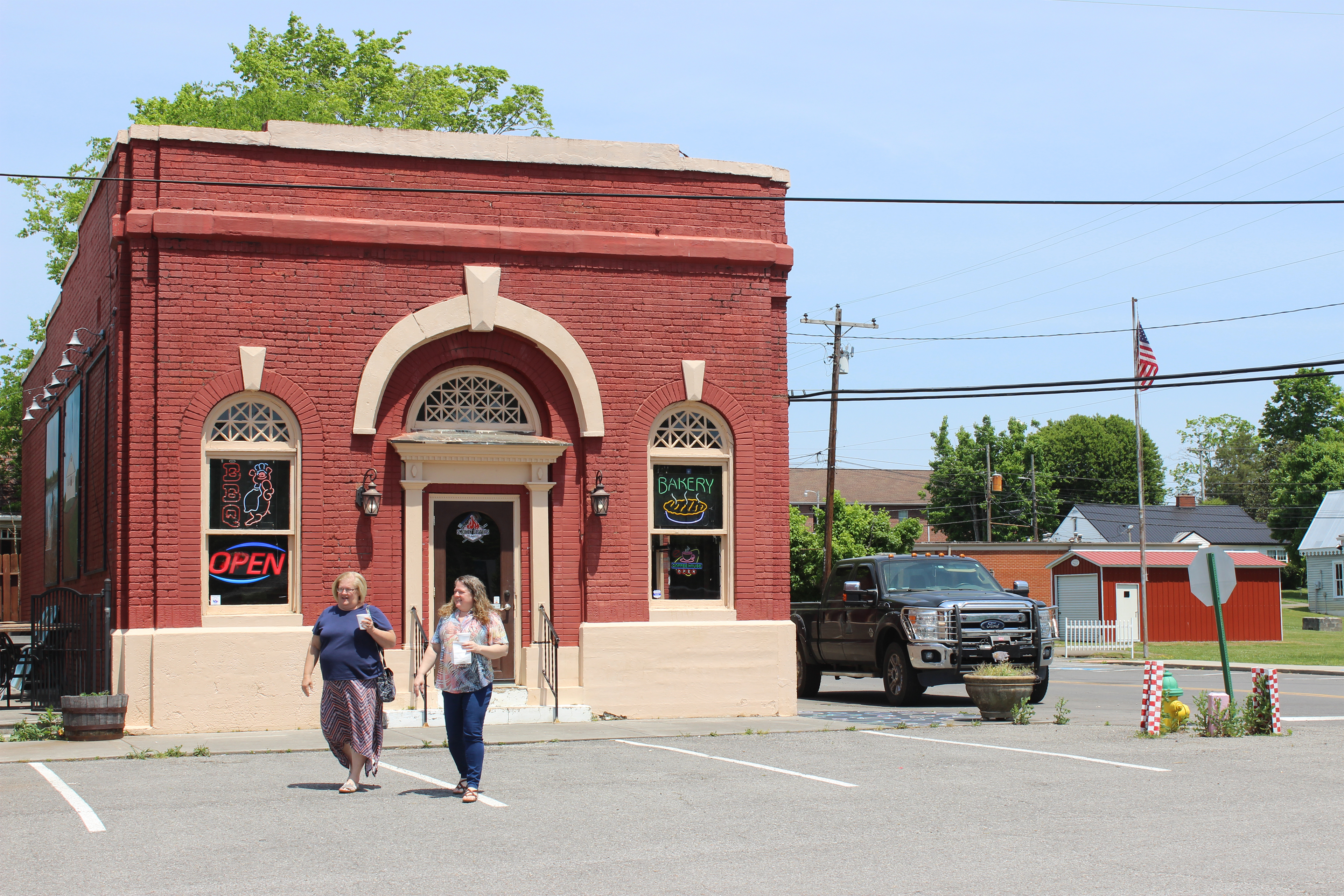 Two people walk past a building in Decatur, Tennessee on a sunny day.