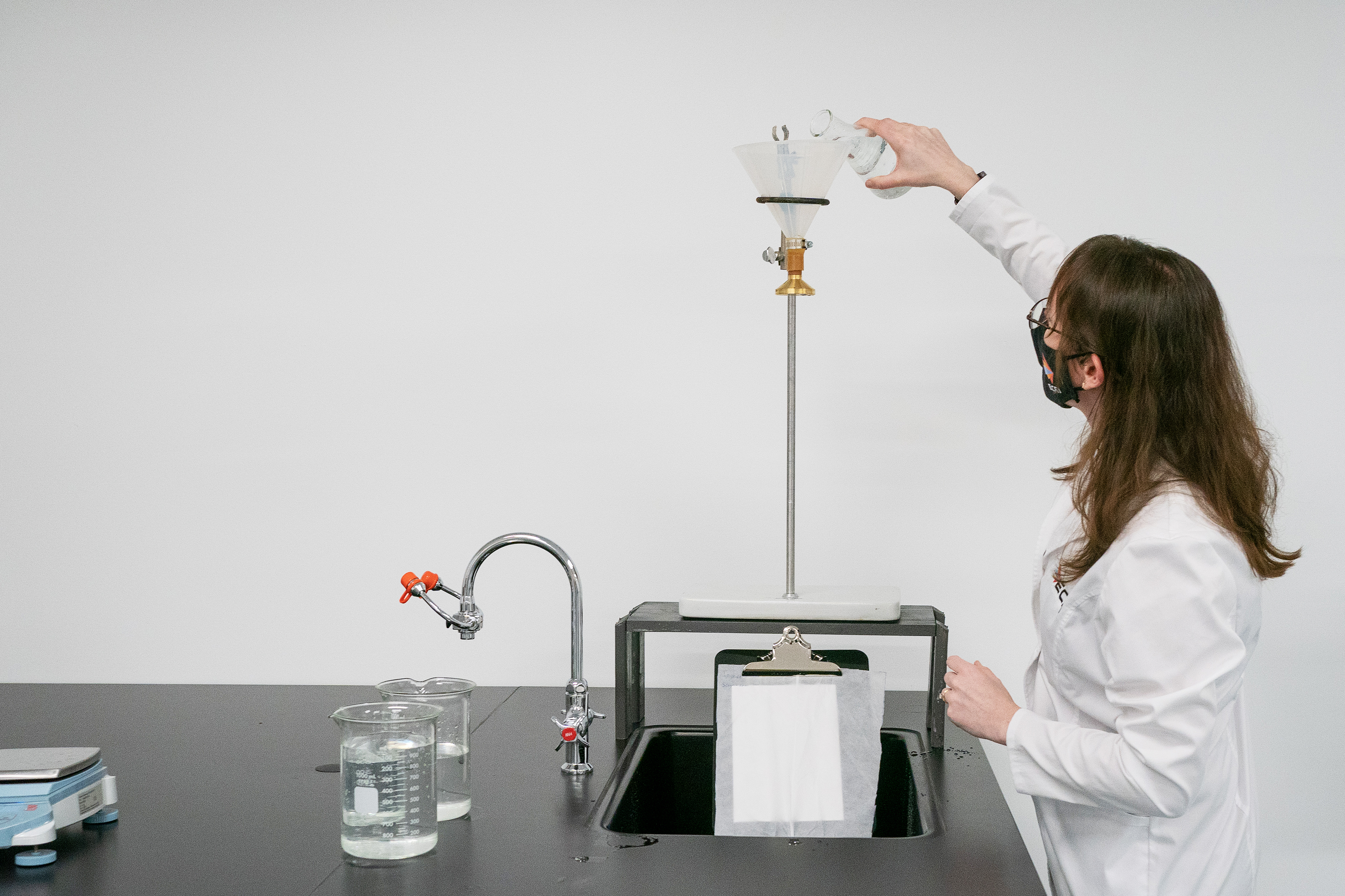 A photo shows Karen Haberland pouring water into a funnel in a laboratory.