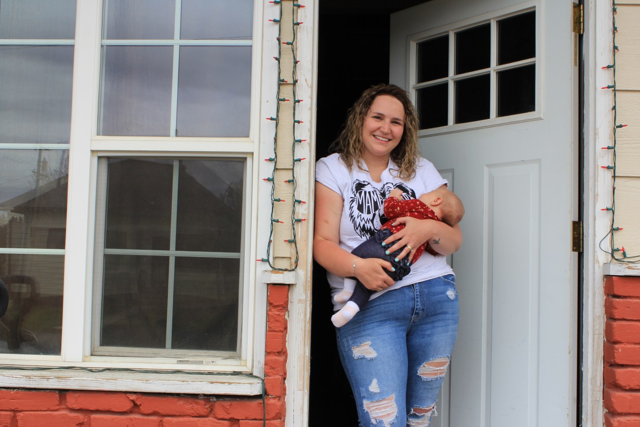 Haley Rehm holds her 2-month-old baby in the doorway of her home just across the street from the Continental mine in Butte, Montana.