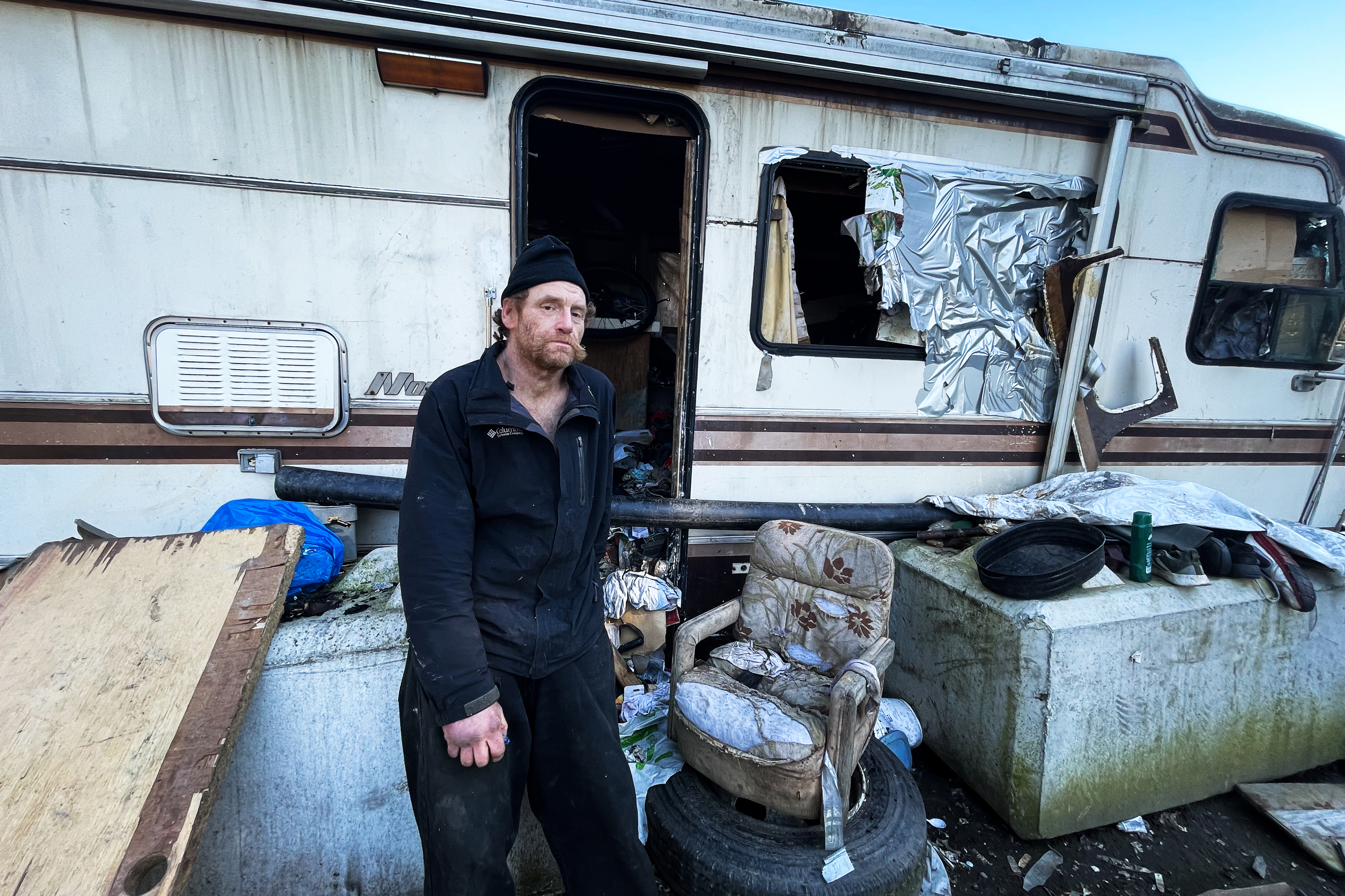 A photo shows Paul Hunter standing in front of an RV. Trash and debris surrounds him.