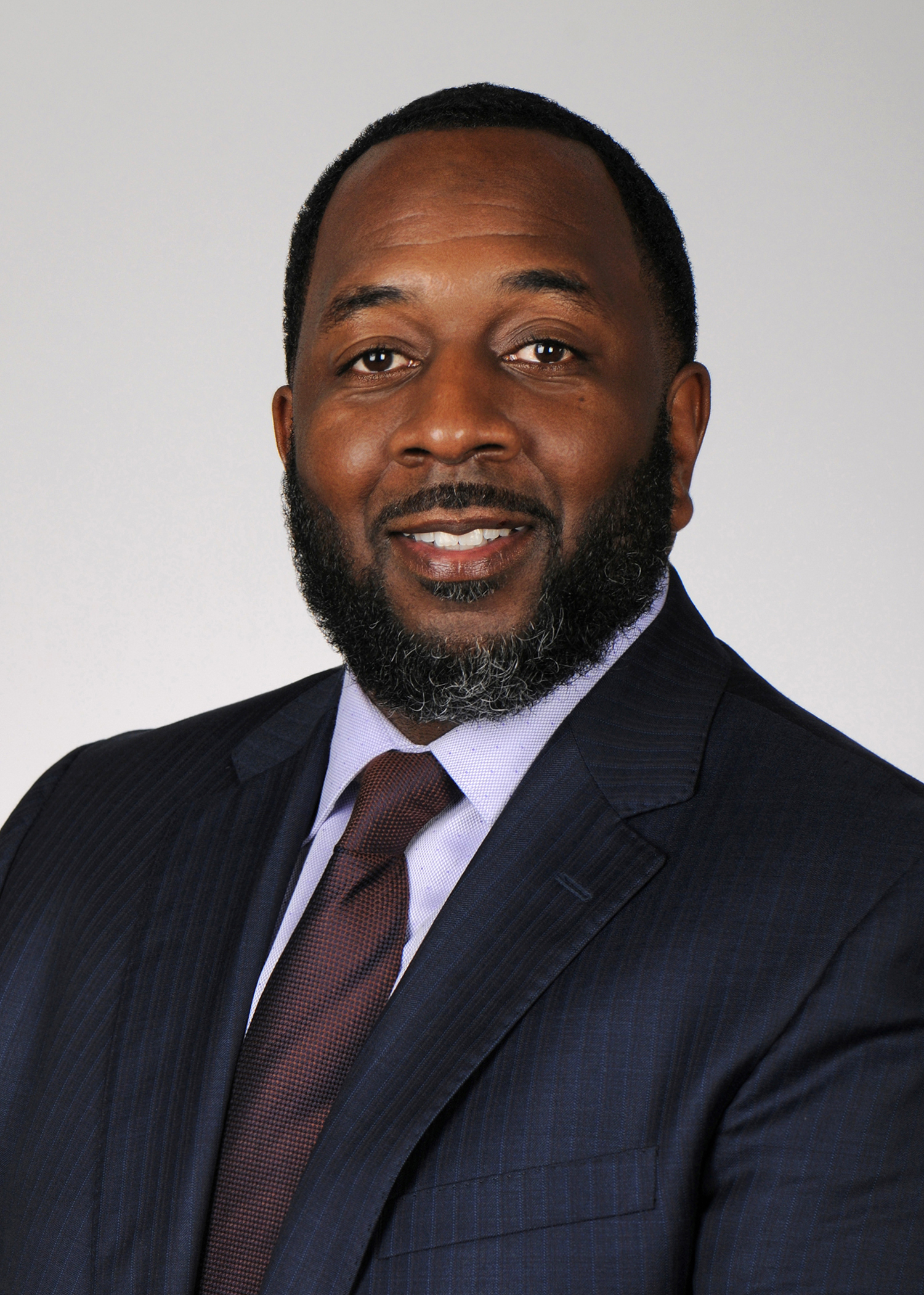 A headshot portrait of Quenton Tompkins is seen. He is smiling.