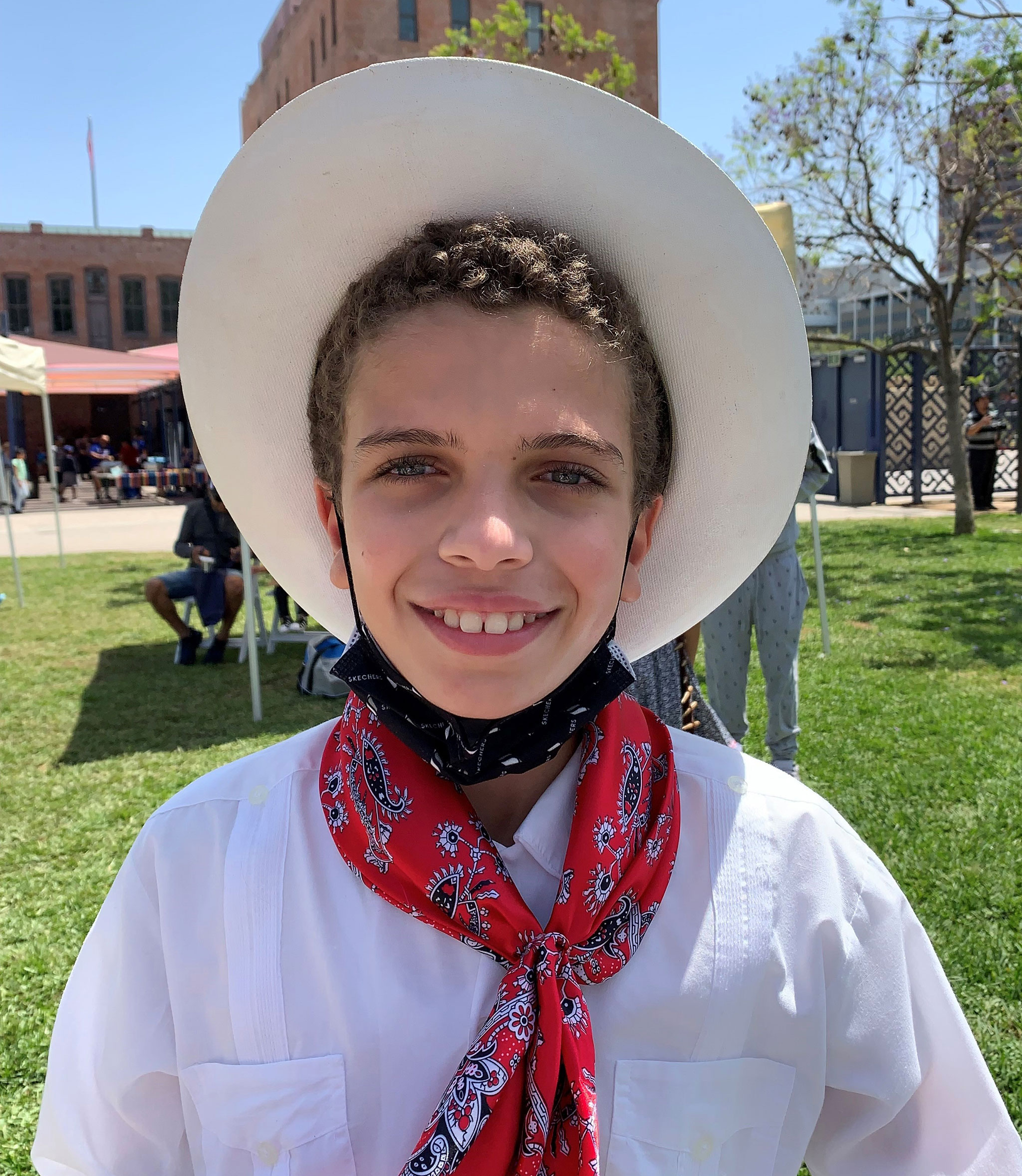 A boy stands outside and smiles at the camera.