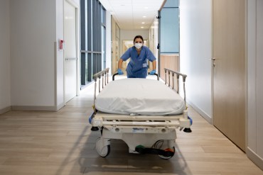 A nurse pushes a gurney down a hallway inside of a hospital.