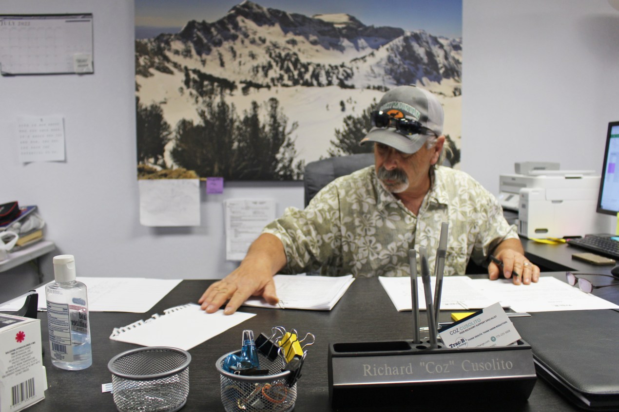 A photo shows Richard Cusolito sitting at his desk, filling out paperwork.